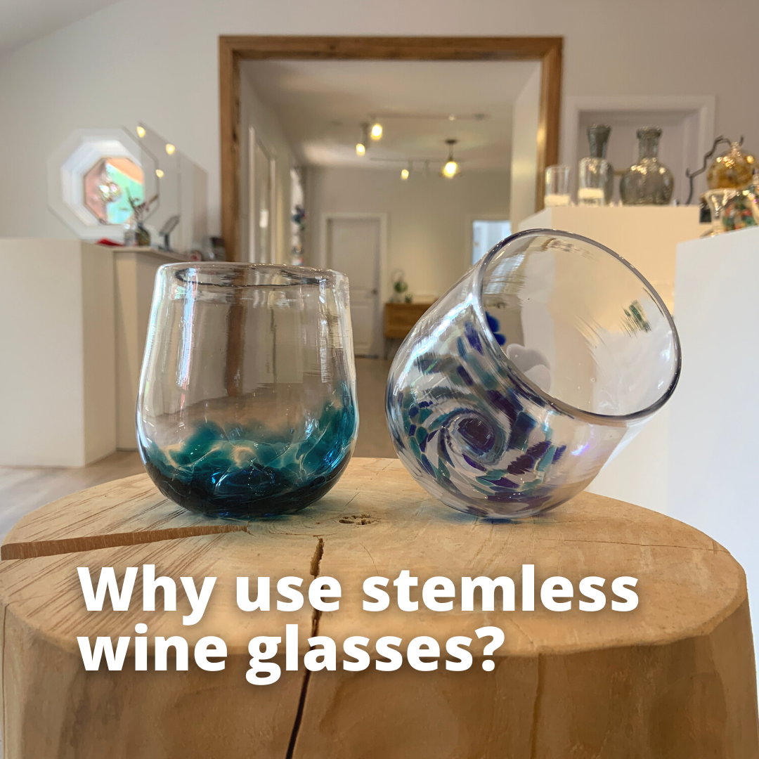A teal blue stemless wine glass and a blue and white stemless wine glass sit on a log in Gray Art Glass gallery. Text reads "Why use stemless wine glasses?"