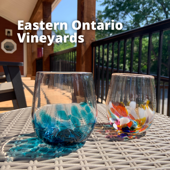 An Ocean Wave and Multi handblown wine glass rest on a patio table. Text reads "Eastern Ontario Vineyards."