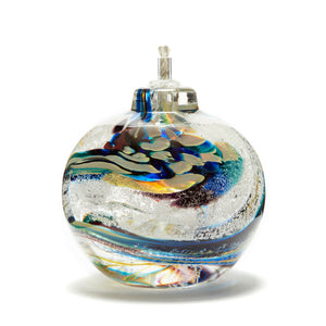 Round memorial glass art eternal flame oil lamp with cremation ash. Red, blue, purple, and green glass. Colour combination is called "Carnival."